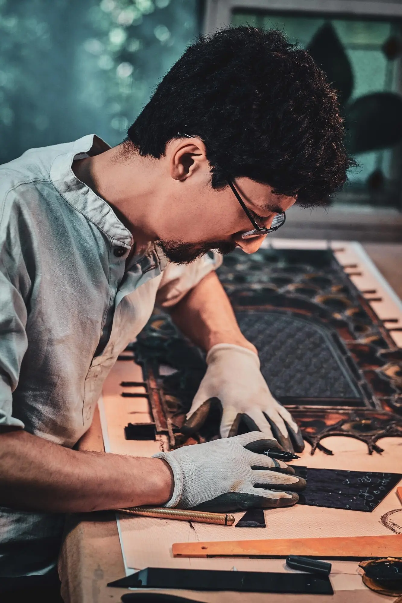 Ein gewissenhafter Restaurator mit Brille zählt in seiner eigenen Werkstatt die richtige Menge für Buntglas.