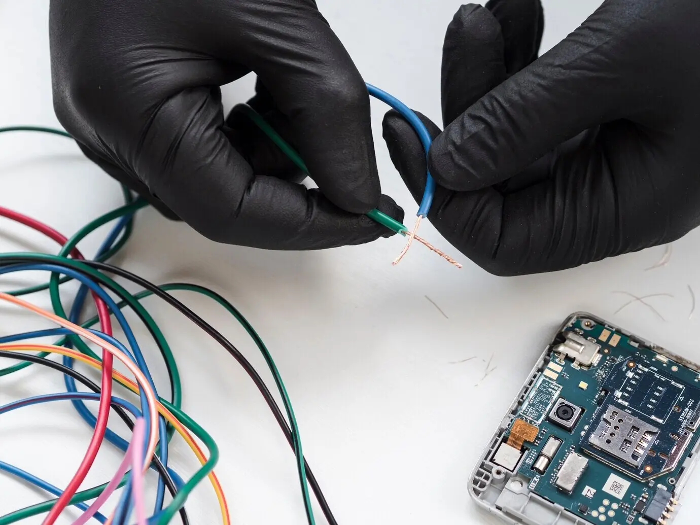 Hände mit schwarzen Handschuhen halten einen Draht